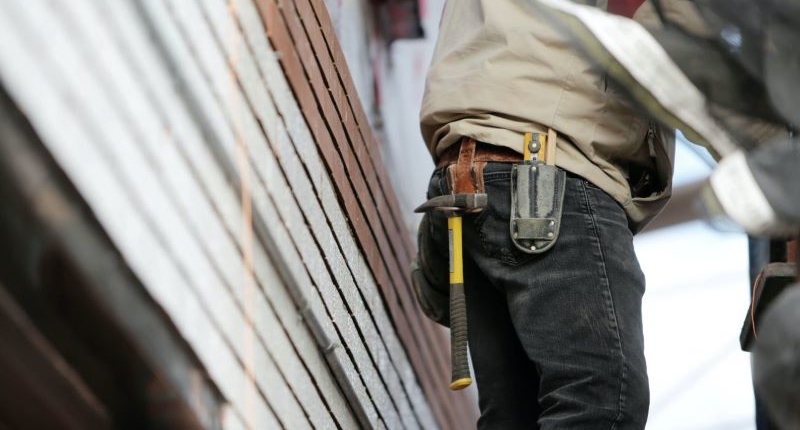 Contractor with Hammer, cutter and tools on his pocket fixing siding