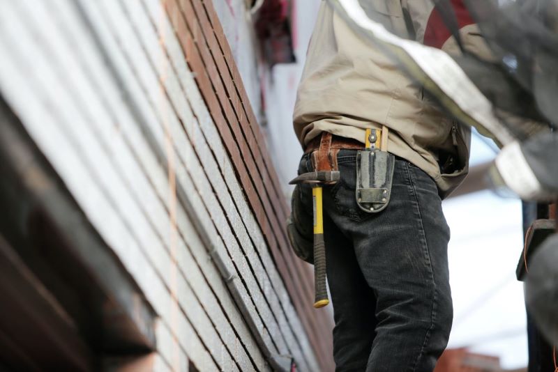 Contractor with Hammer, cutter and tools on his pocket fixing siding