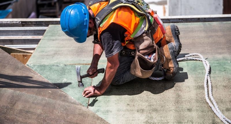 Man with Blue Hat fixing Roof with Nail and Hammer