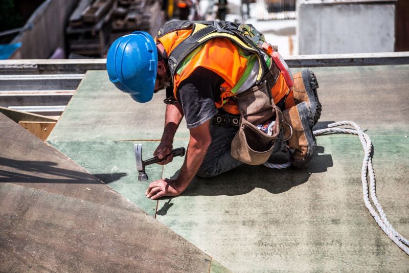 Man with Blue Hat fixing Roof with Nail and Hammer