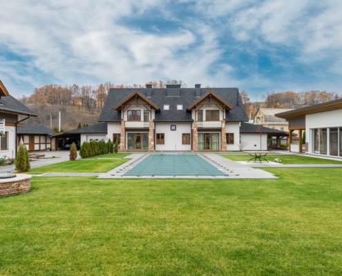 A big two-storey residential house with grey roof and white color walls